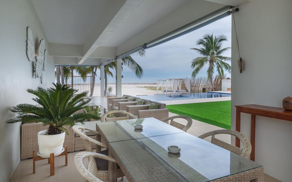 Vela VII Pool Villa, Cha-Am covered terrace with dining table overlooking pool and beach.
