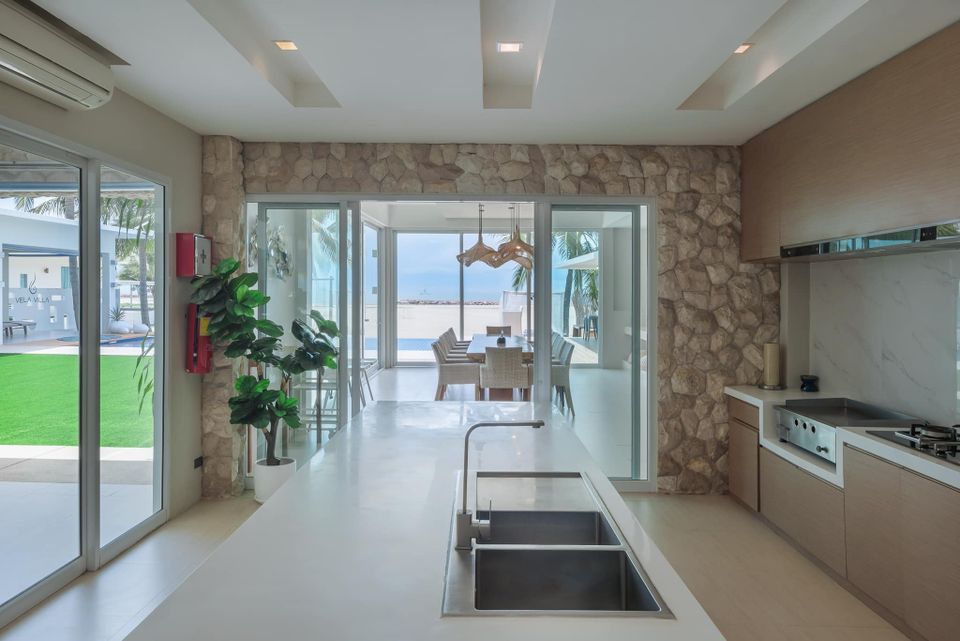Modern kitchen island with dining view at Vela VII Pool Villa, Cha-Am, Thailand.