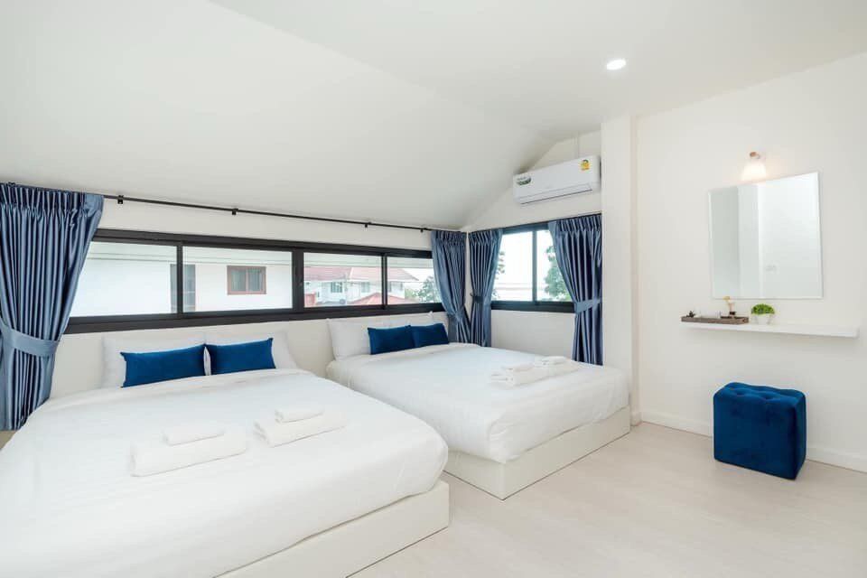 Bright bedroom at View Lay IV Pool Villa, Cha-Am, featuring two queen-sized beds with white linens and blue pillows.