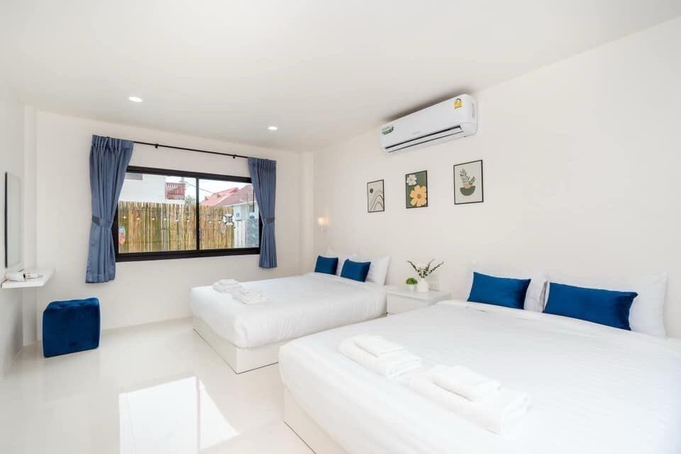 Bright bedroom at View Lay IV Pool Villa, Cha-Am, featuring two comfortable queen-sized beds with white linens and blue pillows.