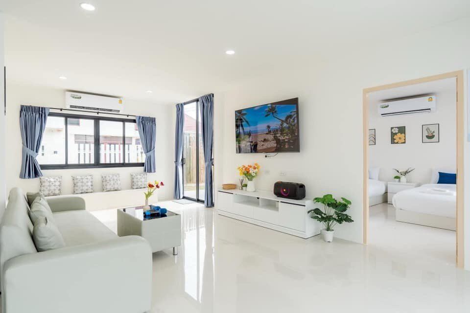 Bright living room at View Lay IV Pool Villa, Cha-Am, featuring a comfortable sofa, wall-mounted TV, and modern decor.