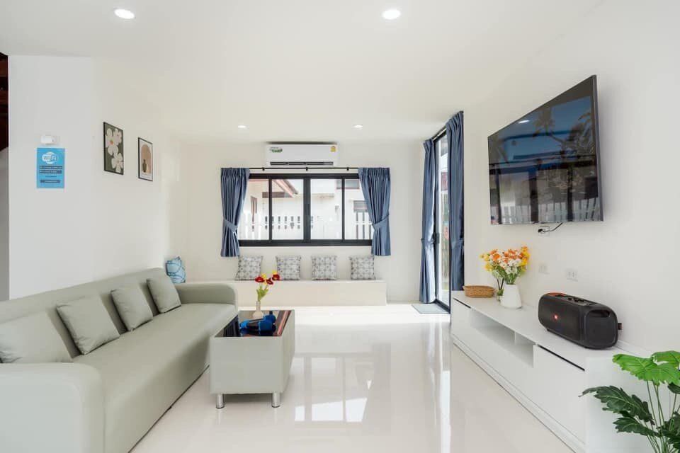 Bright living room at View Lay IV Pool Villa, Cha-Am, with a comfortable sofa, wall-mounted TV, and modern decor.