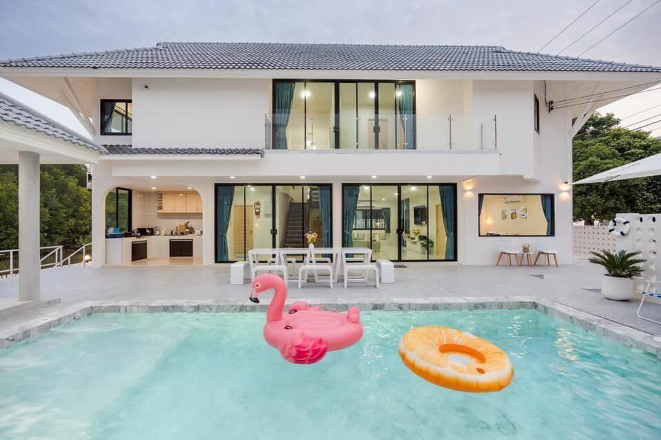 Modern white facade of View Lay IV Pool Villa in Cha-Am, with a swimming pool and outdoor dining area.